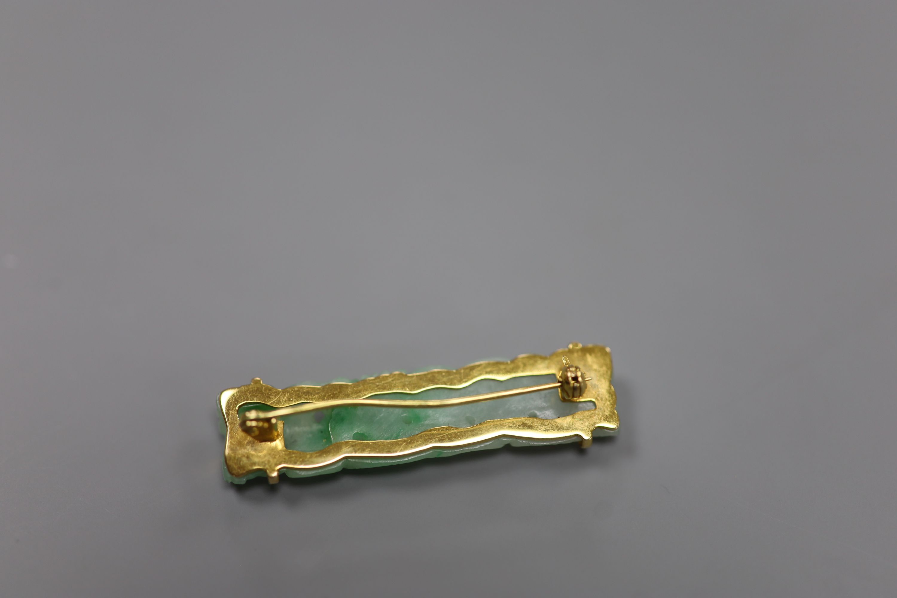 A 14k yellow metal and carved jade set bar brooch, 41mm